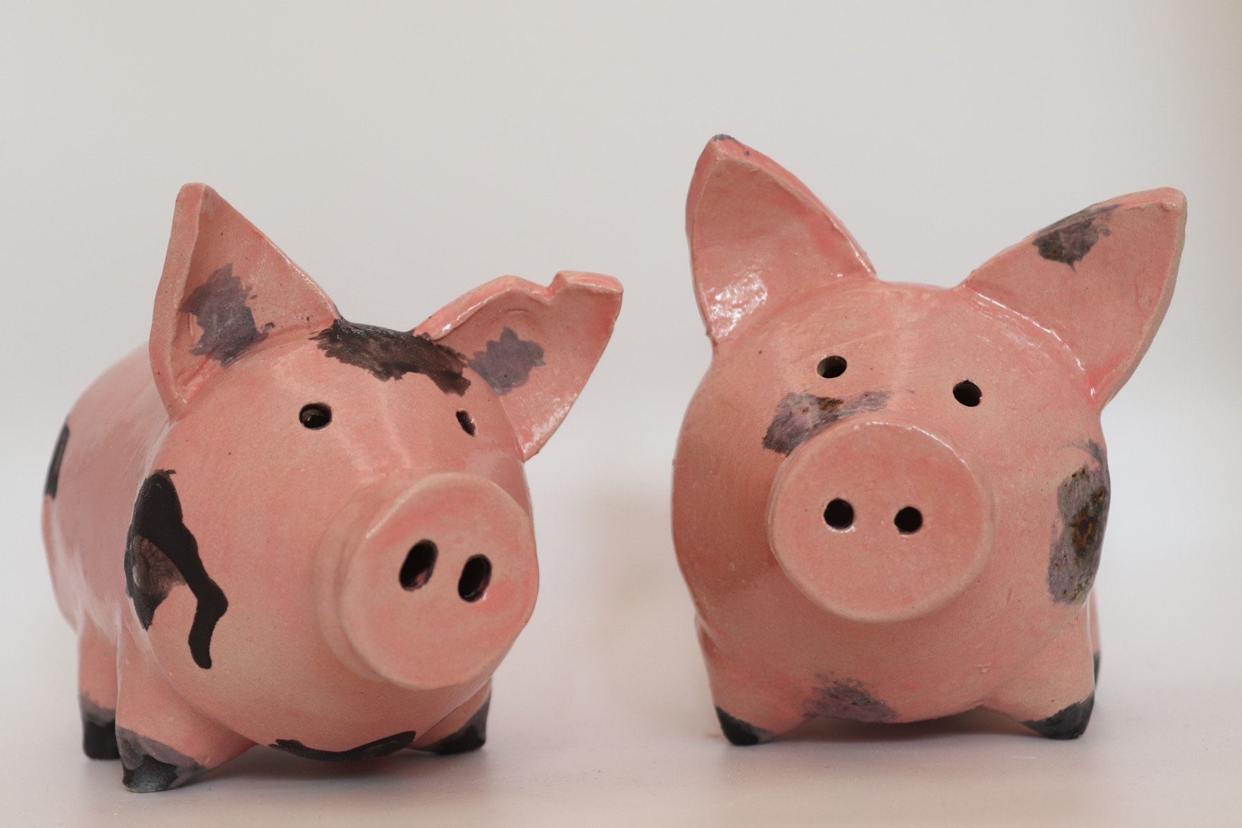 Two pink ceramic piggy-bank tests with different dark markings
