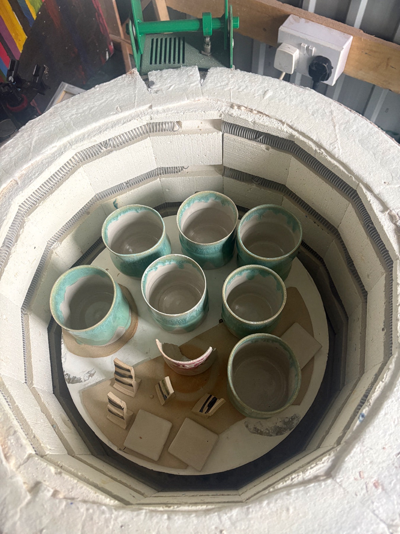 Open kiln with freshly fired cups and test tiles after a glaze firing